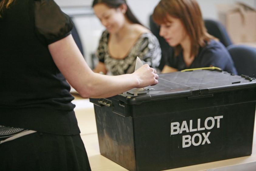 image of votes being cast in a ballot box